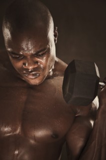 Grimacing African American man lifting weights