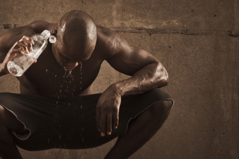 African American man pouring water over himself after exercise