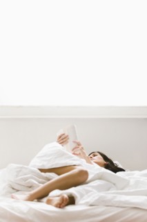 Caucasian woman reading book in bed
