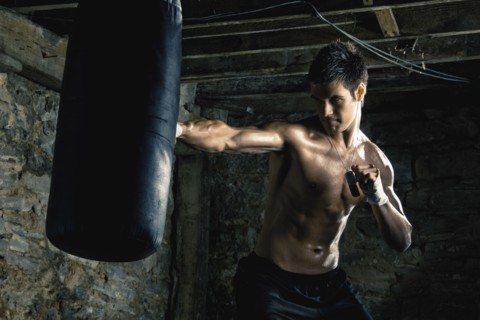 Caucasian boxer training and hitting punching bag