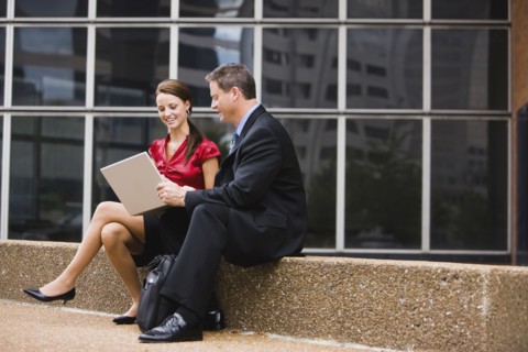Caucasian co-workers using laptop together outdoors