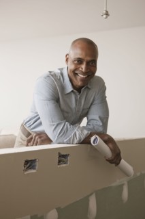 African American man standing in unfinished room with blueprints