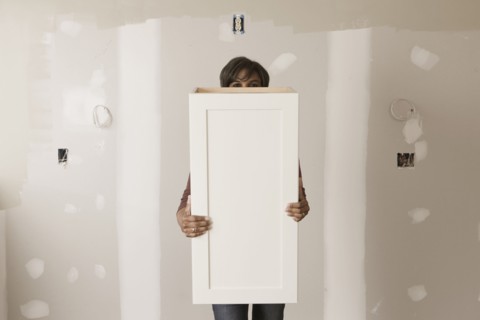Mixed race woman holding cabinet door in unfinished room