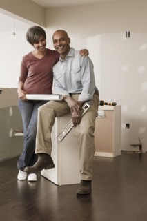 Couple with level and blueprints in unfinished room