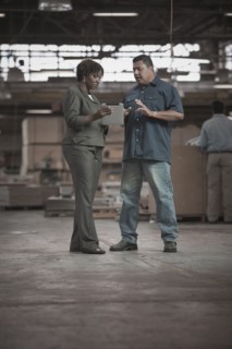 Businesswoman talking to worker in warehouse
