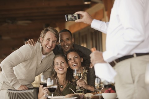 Man taking photographs of friends in restaurant