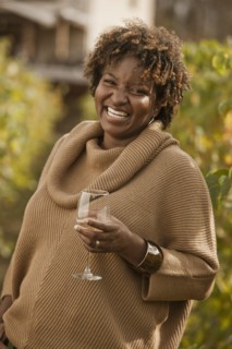 Black woman drinking wine in vineyard
