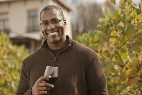 Black man drinking wine in vineyard