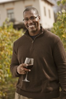 Black man drinking wine in vineyard