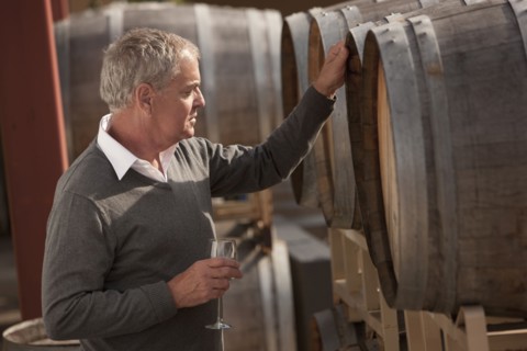 Caucasian man drinking wine near wine barrel