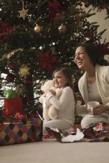 Mixed race mother and daughter opening gifts Christmas morning