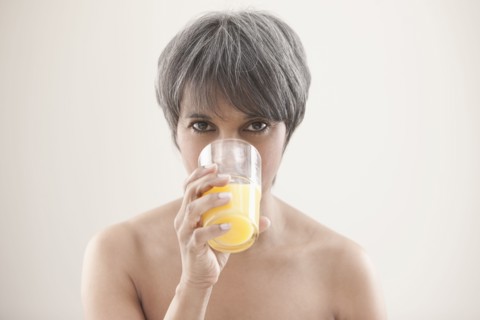 Mixed race woman drinking orange juice