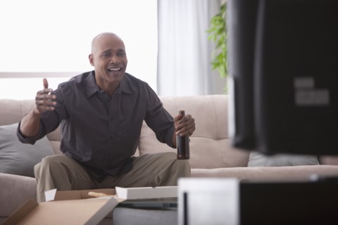 Black man drinking beer and watching television
