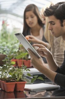 Students working in greenhouse with digital tablet