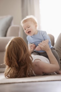Caucasian mother laying on floor playing with son
