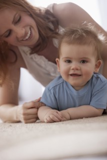 Caucasian mother laying on floor playing with son