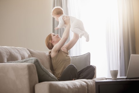 Caucasian mother on sofa lifting son