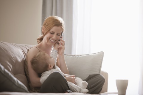 Caucasian mother holding son and talking on cell phone