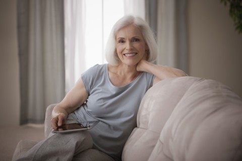 Caucasian woman sitting on sofa with digital tablet