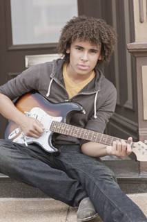 Mixed race teenager playing electric guitar