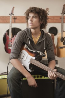 Mixed race teenager sitting with electric guitar