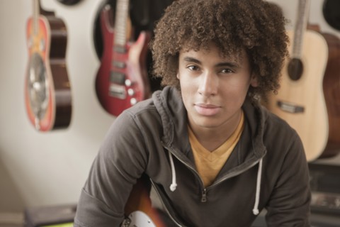 Mixed race teenager sitting with guitars