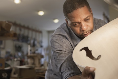 Native American man making guitar in workshop