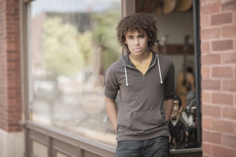 Mixed race teenager standing outside music store