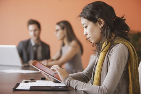 Mixed race businesswoman using tablet computer in meeting