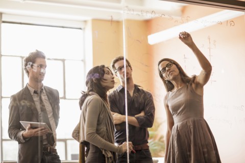 Business people writing on glass wall