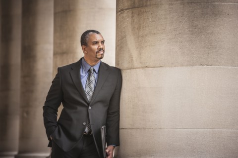 Mixed race businessman leaning on column