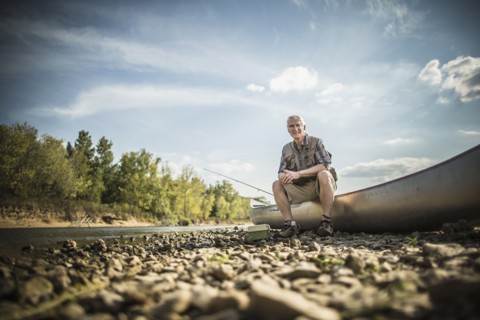 Older Caucasian man sitting in canoe on riverbed