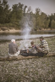 Three generations of Caucasian men relaxing near campfire
