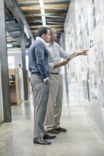 Businessmen examining photographs on wall in office