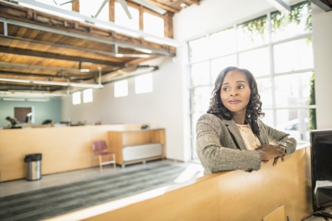 African American businesswoman standing over cubicle in office