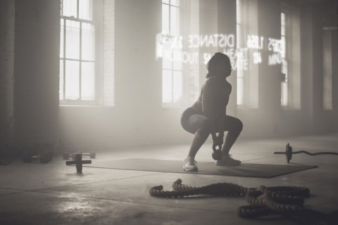 Virtual words circling Black athlete lifting kettlebell