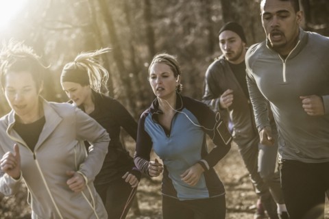 Runners jogging on dirt path in forest