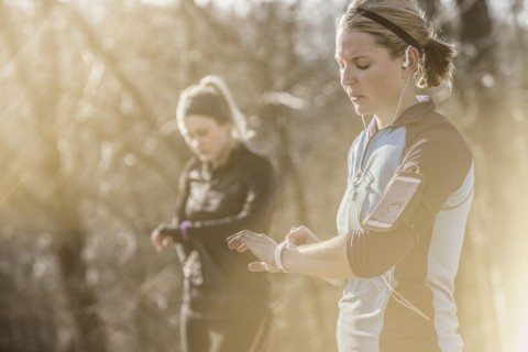 Caucasian runners checking fitness watches in forest