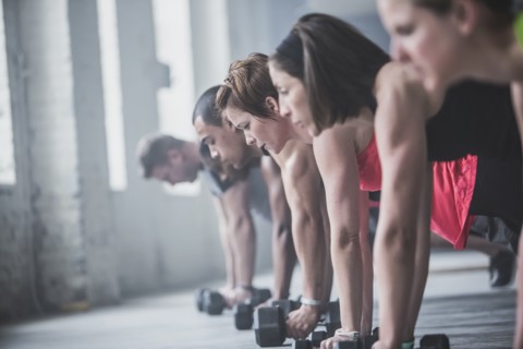 Athletes doing push-ups and lifting weights on floor