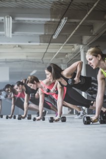 Athletes doing push-ups with dumbbells on floor