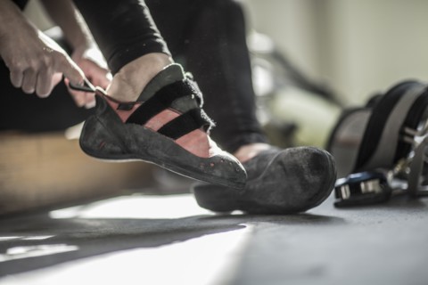 Athlete pulling on climbing shoes in gym
