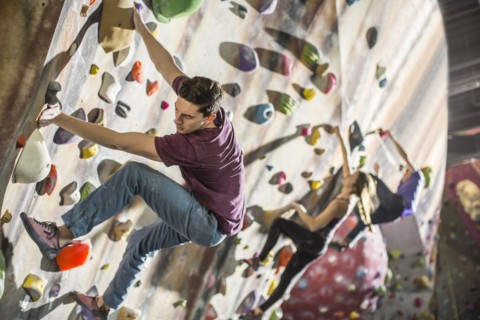 Athletes climbing rock wall in gym
