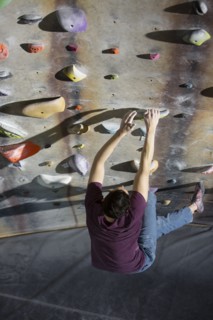 High angle view of athlete climbing rock wall in gym