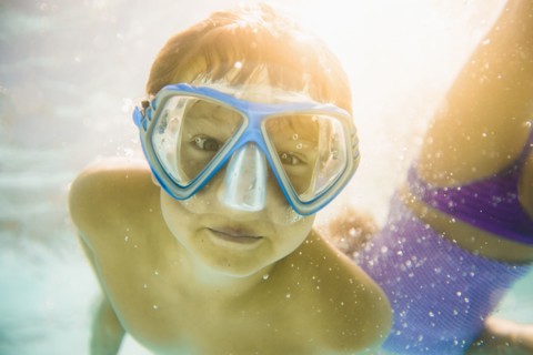 Caucasian boy swimming underwater in swimming pool