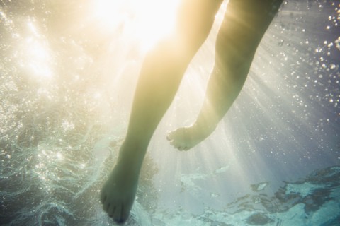Caucasian girl swimming underwater in swimming pool