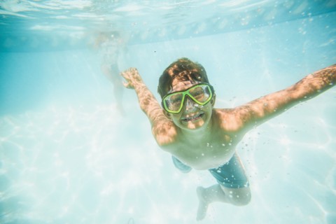 Caucasian boy swimming underwater in swimming pool