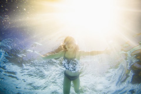 Caucasian girl swimming underwater in swimming pool