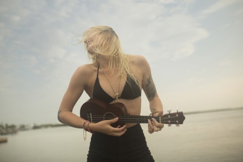 Caucasian woman playing ukulele on beach