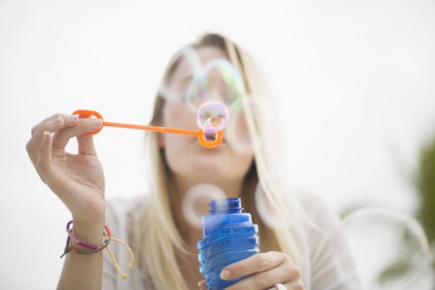 Caucasian woman blowing bubbles outdoors