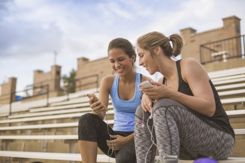 Women using cell phones on bleachers